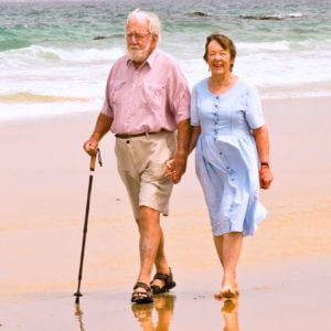 an elderly couple walking on the beach