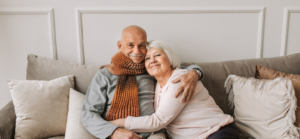 An elderly man and woman sitting on a couch.